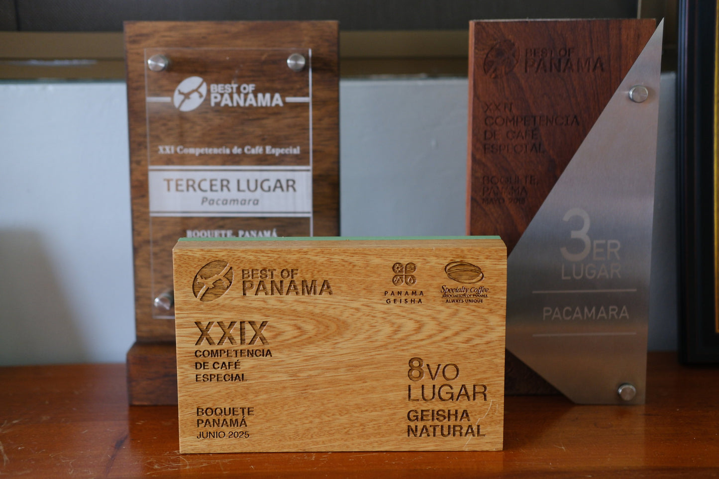 Three wooden and metallic commemorative trophy plaques from the XXIX Competencia de Café Especial (Best of Panama) on a wooden surface.