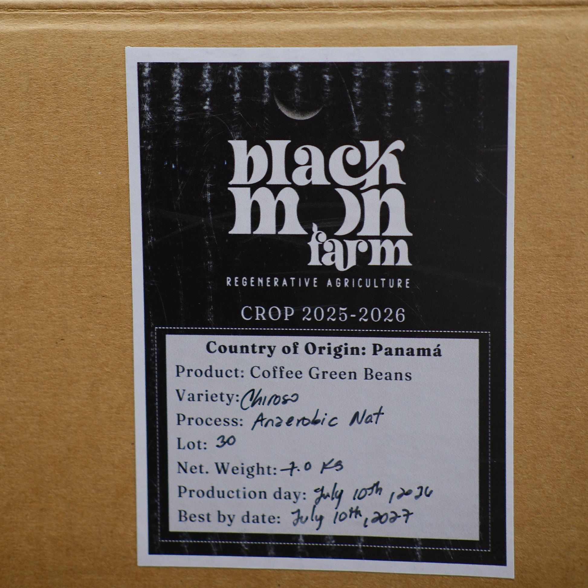 A close-up of a cardboard shipping box with a printed label from Black Moon Farm. The label details the crop year 2025-2026, country of origin Panama, variety Chibo50, and other shipping information.